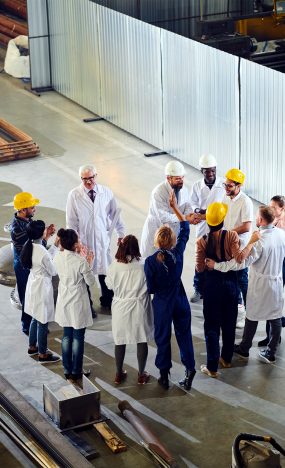 High angle view at group of factory workers protesting emotionally during meeting with management in industrial workshop, copy space